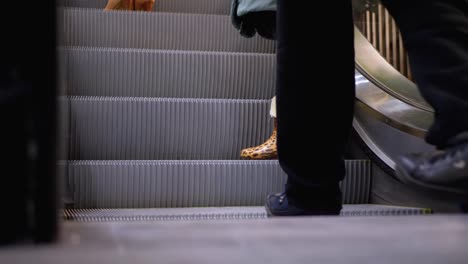 Piernas-de-personas-moviéndose-en-un-ascensor-de-escaleras-mecánicas-en-el-centro-comercial.-Pies-de-comprador-en-Escalera-Saltadora-en-el-Centro-Comercial