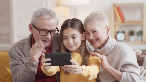 Kaukasische-Großeltern-und-Enkelin-machen-Selfie-auf-Smartphone