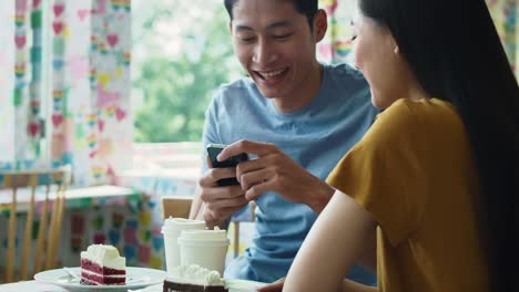 Vista-de-mano-de-la-pareja-usando-el-teléfono-móvil-en-la-cafetería