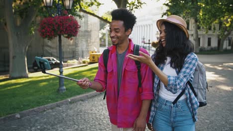 Afro-american-male-and-female-recording-video-for-subscribers-on-smartphone-while-walking-along-city-street