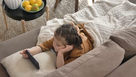 Little-girl-with-bows-and-plaid-watches-cartoons-on-phone