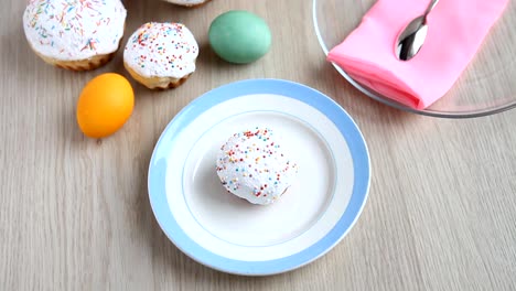 Hands-take-away-from-the-table-a-plate-with-a-Easter-cake-with-white-icing.