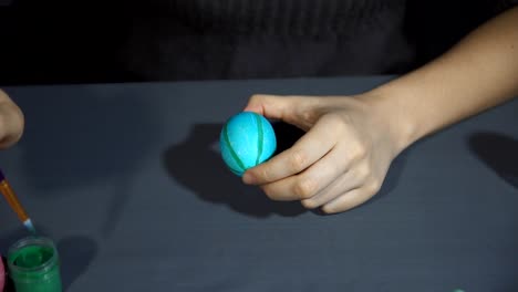 Female-hands-painting-the-egg-decoration-for-easter-over-a-gray-background.