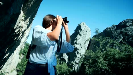 Young-woman-with-backpack-taking-a-photo-in-grand-canyon