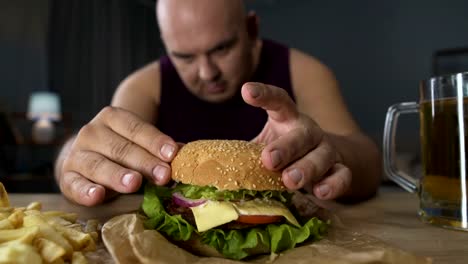 Comer-en-exceso,-obeso-hombre-cocinar-hamburguesa-grande,-gourmet-admirando-su-comida,-primer-plano