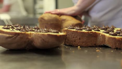 manos-de-chef-de-pastelería-rellenos-de-tortas-de-pan-dulce-de-Pascua-con-chocolate,-closeup-en-la-encimera-en-confitería