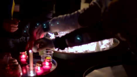 Group-of-people-lighting-dozens-of-candles-in-plastic-glasses,-light-at-night