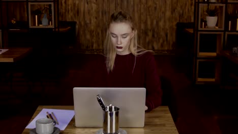 Portrait-of-young-blond-female-content-manager,-who-is-working-on-her-laptop-in-modern-cafe