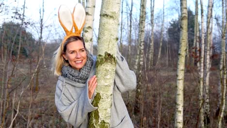 Cinemagraph-de-mujer-rubia-con-orejas-de-conejo-mirando-desde-detrás-de-un-árbol