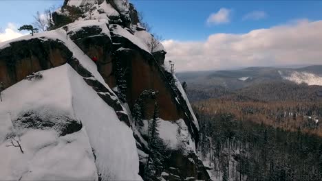 Aerial-view-of-a-rock-climber-climbing-a-steep-cliffs-during-a-sunny-winter-day.