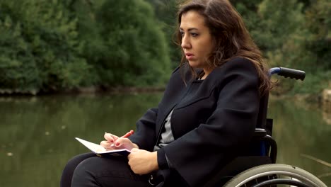 woman-on-wheelchairs-writes-a-love-letter-near-the-lake