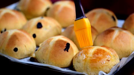 Hausgemachte-Ostern-traditionelle-Hot-Cross-Buns.-Weibliche-Hände-mit-Sirup-bedecken.