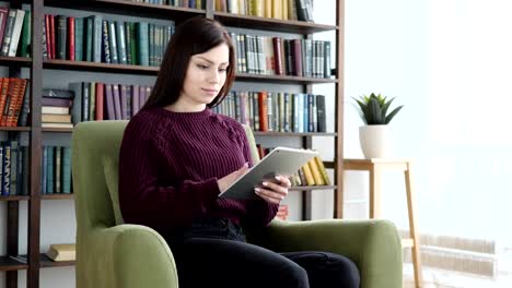 Mujer-sentada-en-Casual-silla-navegación-Internet-en-Tablet