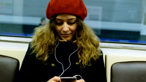 Schöne-kaukasischen-Frau-mit-Kopfhörern-mit-Handy-in-der-u-Bahn