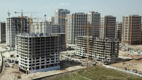 Vista-aérea.-Construcción-de-un-moderno-barrio-con-infraestructura-desarrollada-y-apartamentos-residenciales.-Un-sitio-de-construcción-con-grúas-y-edificios-altos.-Venta-y-alquiler-de-bienes-inmuebles