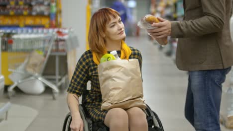 Mujer-con-discapacidad-en-silla-de-ruedas-de-compras-en-el-mercado-de-comestibles-con-su-novio