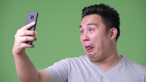 Young-handsome-overweight-Asian-man-against-green-background