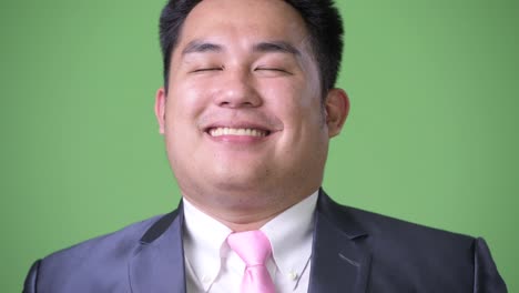 Young-handsome-overweight-Asian-businessman-against-green-background