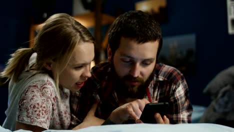 Young-couple-surfing-smartphone-on-bed