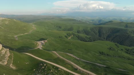 Antenne:-Flug-über-eine-hohe-Felswand,-offenbart-einen-Blick-des-Passes-in-Russland-im-Nordkaukasus.-Luftaufnahmen-von-der-Straße-in-der-untergehenden-Sonne.-Flug-neben-dem-Felsen