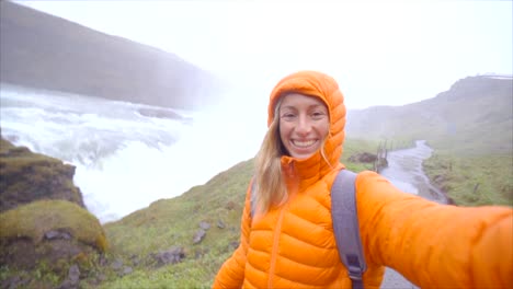 SLOW-MOTION-Selfie-Porträt-der-jungen-Frau-in-der-Nähe-von-riesigen-Wasserfall,-Island