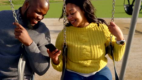 Happy-couple-using-mobile-phone-in-the-park-on-a-sunny-day-4k