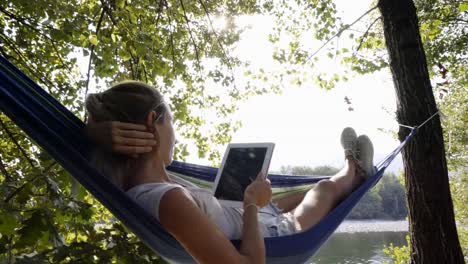 Young-woman-using-digital-tablet-on-hammock