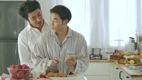 Attractive-young-asian-gay-couple-having-breakfast-in-kitchen.-Man-cooking-breakfast-for-him-boyfriend-with-attractive-smiling.-People-with-gay,-homosexual,-relationship-concept.