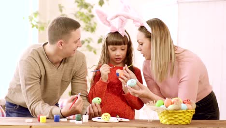 Familie-mit-Tochter-schmücken-Ostereier-und-schauen-in-die-Tochter.