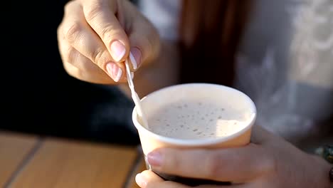 hermosa-mujer-caucásica-joven-sentada-después-del-trabajo-en-la-noche-en-un-café-de-la-calle-bebiendo-café-y-charlando-en-las-redes-sociales-usando-un-teléfono-inteligente.