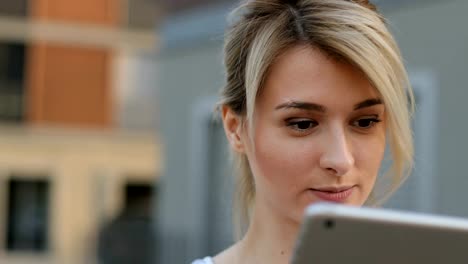 Close-up-portrait-of-young-female-student-using-tablet-computer-outside.-Girl-doing-online-shopping-on-tablet-pc