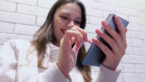 Lächelnde-Frau-tippt-eine-Nachricht-auf-Handy-sitzen-und-wartet-auf-jemanden-im-Café.