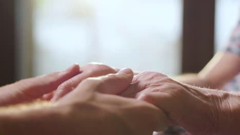 young-person-helps-her-grandmother-to-get-up-taking-her-hands.