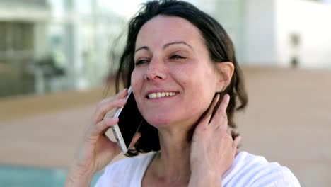 Smiling-beautiful-woman-talking-to-interlocutor-through-phone.