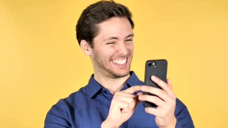 Casual-Young-Man-celebrando-el-éxito-durante-el-uso-de-smartphone-sobre-fondo-amarillo