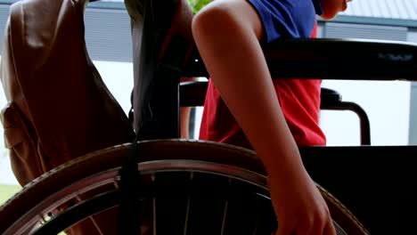 Side-view-of-disabled-African-American-schoolboy-moving-his-wheelchair-in-school-corridor-4k