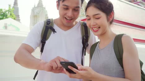 Traveler-Asian-couple-direction-on-location-map-in-Bangkok,-Thailand,-couple-using-mobile-phone-looking-on-map-find-landmark-while-spending-holiday-trip.-Lifestyle-couple-travel-in-city-concept.