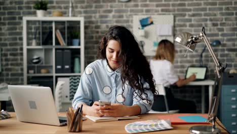 Fröhliche-Mädchen-mit-Smartphone-berühren-Bildschirm-arbeiten-im-Büro-am-Schreibtisch