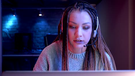 Closeup-shoot-of-young-attractive-female-blogger-with-dreadlocks-in-headphones-playing-video-games-and-streaming-live-with-the-neon-background