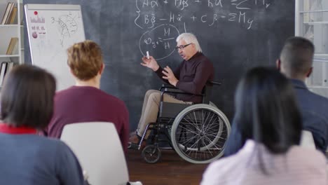 Mature-Disabled-Professor-Writing-on-Chalkboard