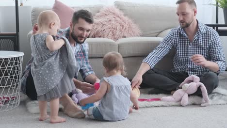 Two-fathers-playing-with-baby-daughters-at-home