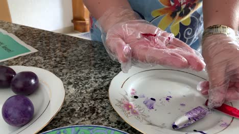 A-woman-in-gloves-paints-eggs