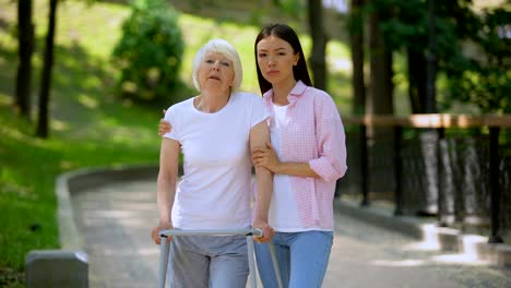 Sad-aged-patient-walking-frame-and-daughter-looking-camera,-social-insecurity