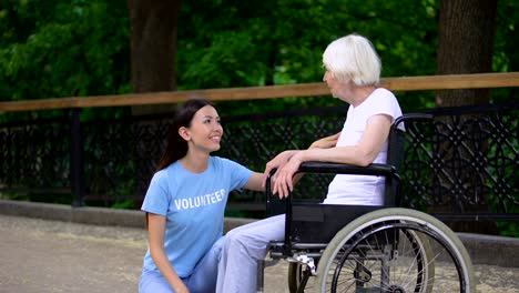 Voluntario-feliz-escuchando-a-la-mujer-mayor-sentada-silla-de-ruedas,-a-las-personas-mayores-les-importa