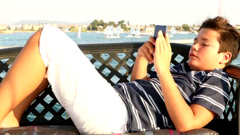 Young-boy-with-smartphone-at-summer-time