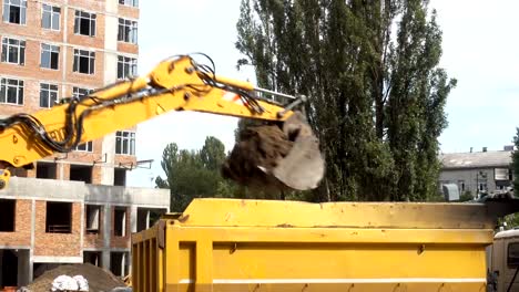 4K-view-of-excavator-bucket-pours-earth-into-the-back-of-a-truck