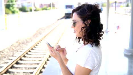 The-girl-is-waiting-for-the-train-at-the-subway-station-and-listening-to-music-on-headphones.-Use-smartphone-in-the-subway.-Underground.-Student-rides-the-subway.