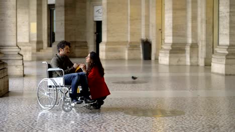 joven-haciendo-una-declaración-de-amor-a-un-hombre-en-silla-de-ruedas.-Amor,-romance