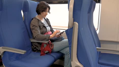 mujer-está-sentada-en-un-tren-sosteniendo-un-teléfono-celular-en-sus-manos-Haciendo-clic-vista-lateral