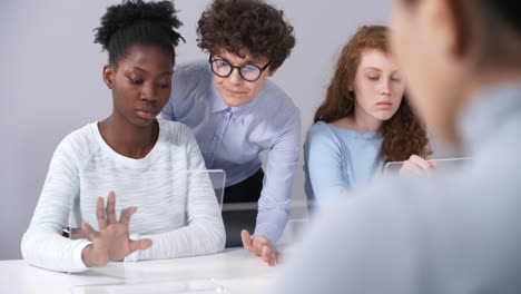 Female-Teacher-Helping-Black-Student-Perform-Task-on-Interactive-AR-Device